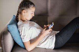 Adolescente tumbada en el sofá mirando su móvil