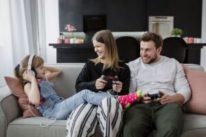 Padres e hija jugando a videojuegos felices.